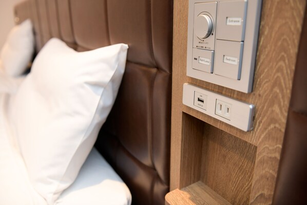 A control panel with a knob and buttons for room settings, a USB port, and a power outlet on a wooden panel.