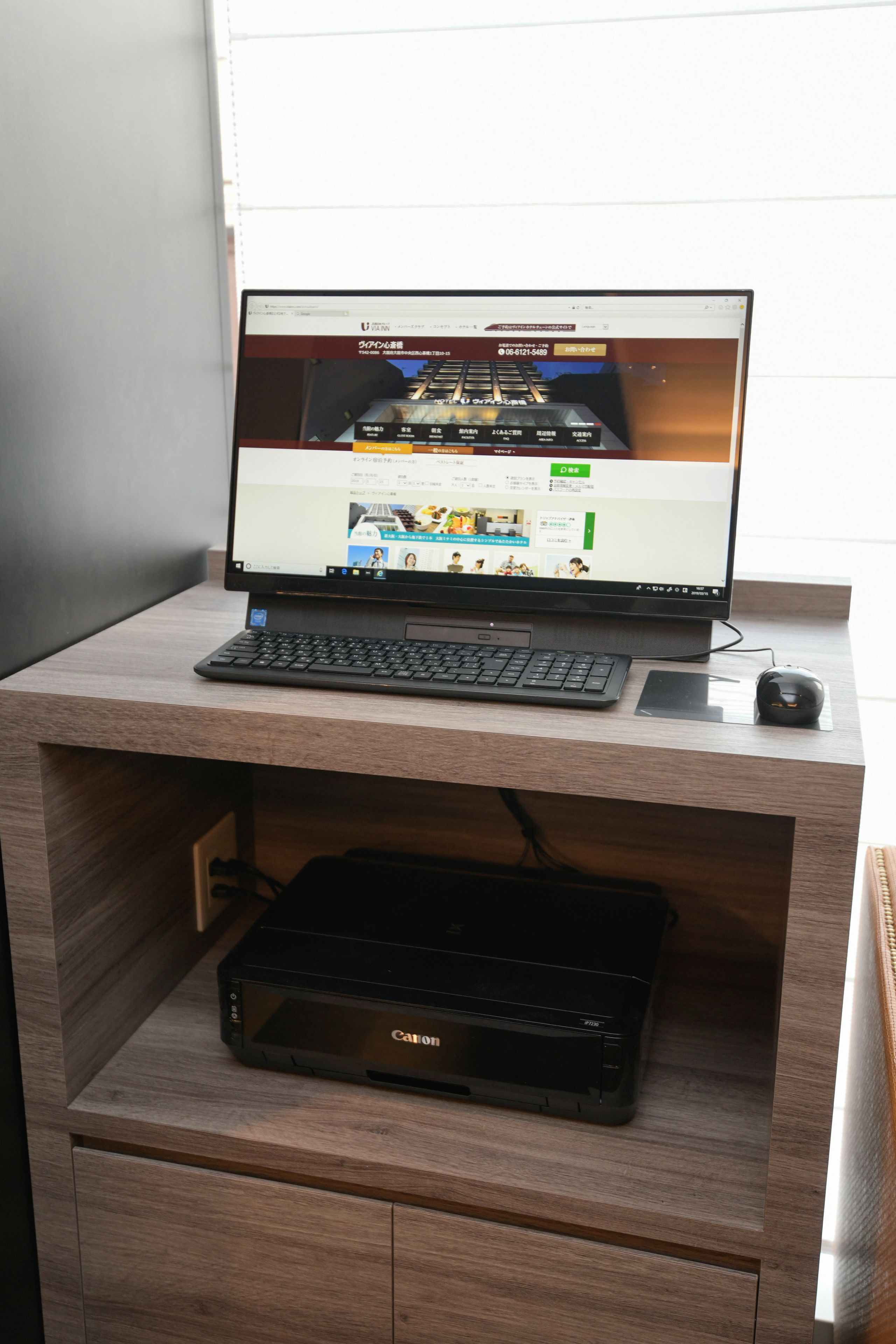 Una computadora portátil sobre un escritorio de madera con una impresora debajo.