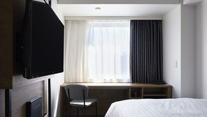 A hotel room with a bed, a desk with a chair, a television, and a window with curtains. - Viainn Shinsaibashi (Osaka)