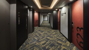 A hotel hallway with numbered doors, carpeted floors, and recessed lighting. - Viainn Shinsaibashi (Osaka)