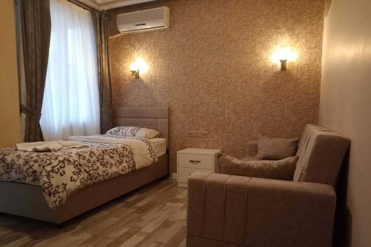 Une chambre à coucher comprenant un lit, une chaise, une table de chevet et un appareil de climatisation.