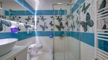 Un baño con cabina de ducha de vidrio, inodoro y lavabo.