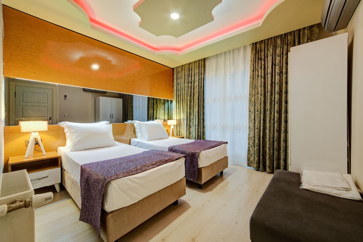 A hotel room with two beds, a desk, a chair, a wardrobe, and a large mirror.