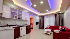 A modern apartment with a kitchen, a living area with a red sofa, and a dining area. - Mersin Vip House (Mezitli)