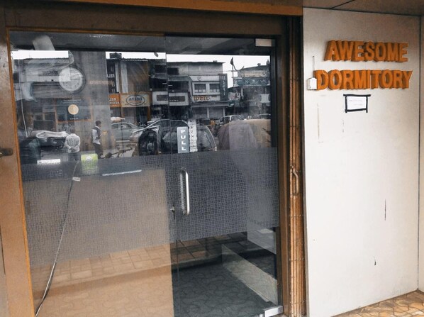 Ein Eingang zu einem Wohnheim mit einem 'PULL'-Schild, einem 'DORMITORY'-Schild und einem Schild mit der Aufschrift 'WE ARE OPEN'.