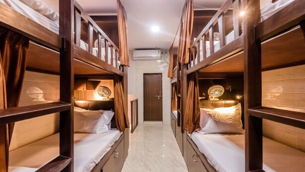 A narrow hallway with bunk beds on either side, a door at the end, and an air conditioning unit on the wall. - Awesome Dormitory (Mumbai)