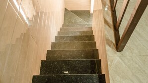 A staircase with black marble steps and wooden handrails, leading to a higher floor. - Awesome Dormitory (Mumbai)