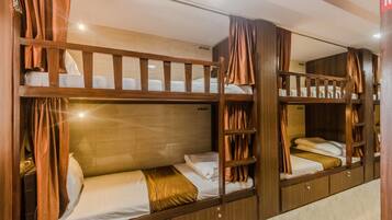 Cozy bunk beds with a simple design, each with a mattress and pillow, are separated by a wooden frame.