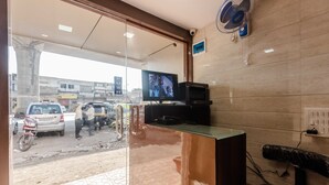 A reception area with a glass door, a television mounted on the wall, and a fan on the ceiling. - Awesome Dormitory (Mumbai)