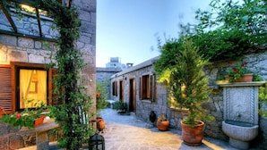 A narrow stone courtyard with potted plants and a bench. - Idasos Tasodalar (Ayvacik)
