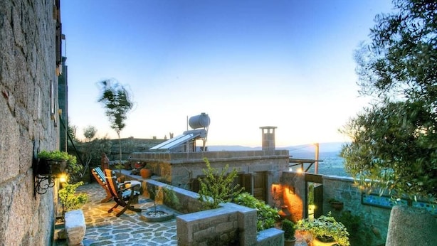 A stone courtyard with a chair, potted plants, and a view of the sea. - Idasos Tasodalar (Ayvacik)