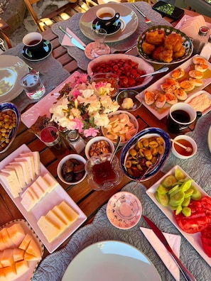 A table set with various food items, including fruits, nuts, and sliced meats, suggesting a meal or buffet setup. - Idasos Tasodalar (Ayvacik)
