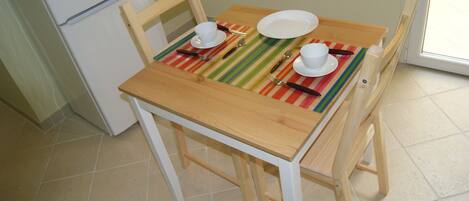 A dining table with chairs, a striped placemat, and white tableware.