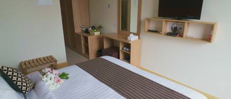A hotel room with a bed, a wooden desk, a television, and a mirror.