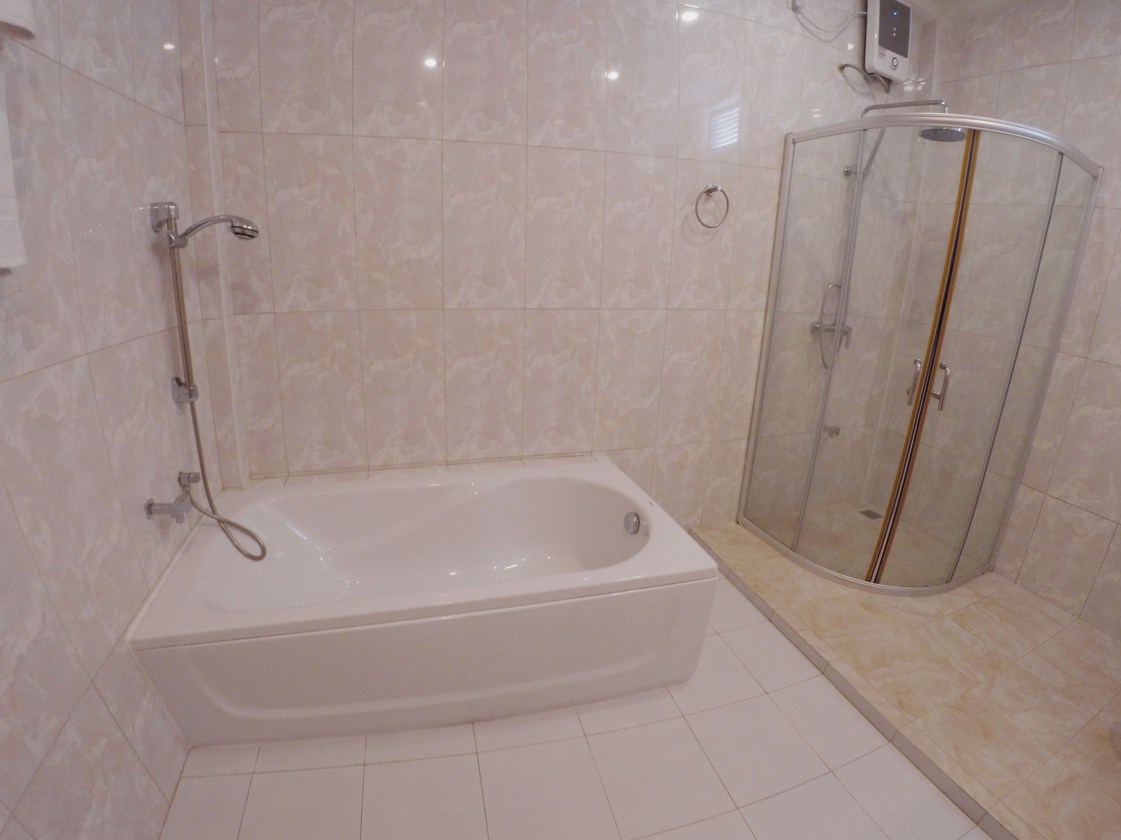 A modern bathroom with a freestanding bathtub, a glass-enclosed shower, and a wall-mounted control panel.