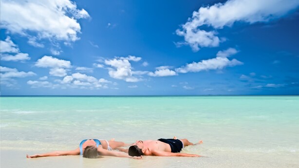 A beach scene with clear turquoise water and a blue sky with clouds. - Ocean Retreat & Spa (Guraidhoo)