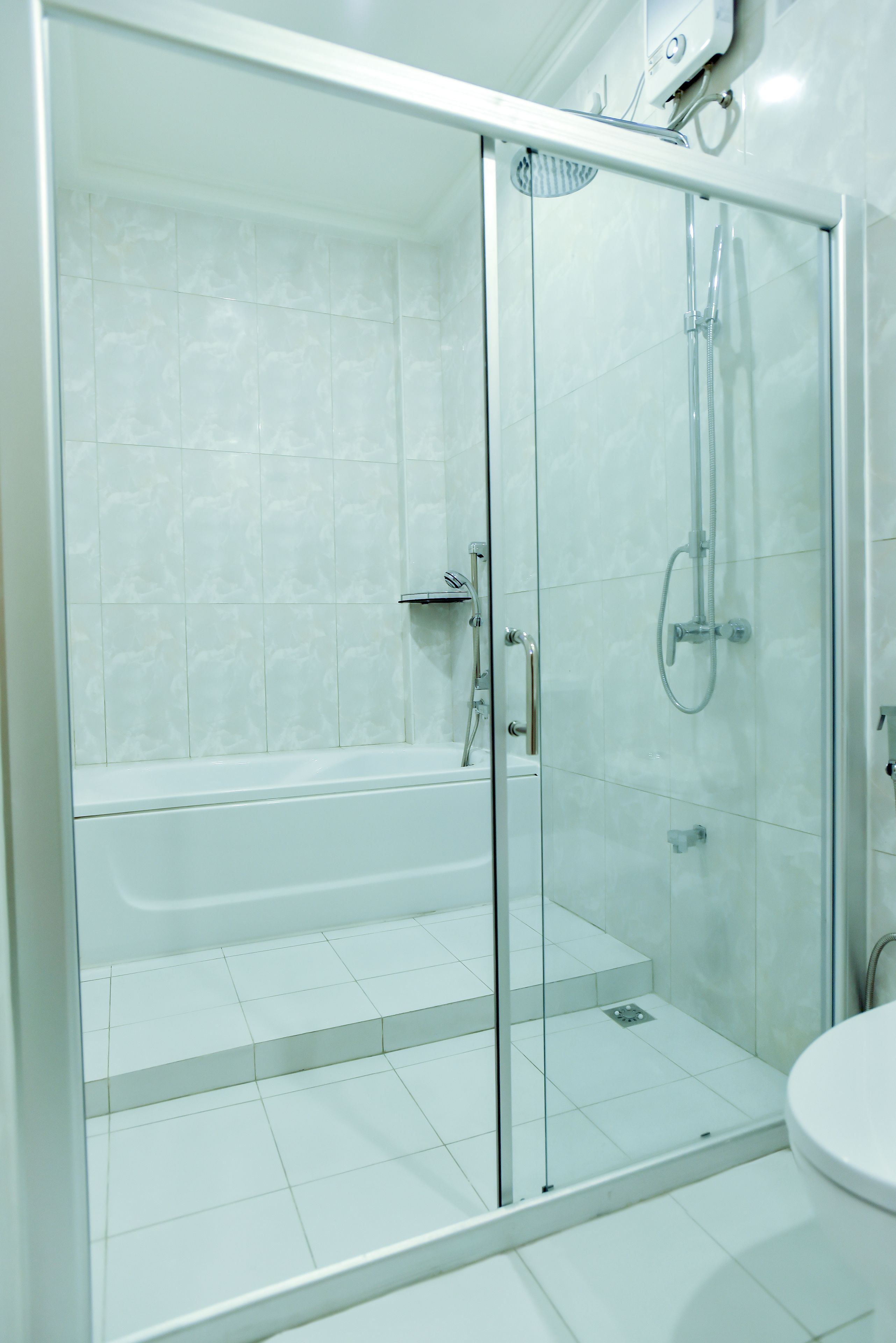 Un baño moderno con ducha envuelta en vidrio, una bañera blanca y un inodoro.