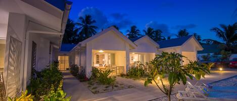 Een resort met meerdere accommodaties in de vorm van bungalows, een zwembad en een goed onderhouden tuin.