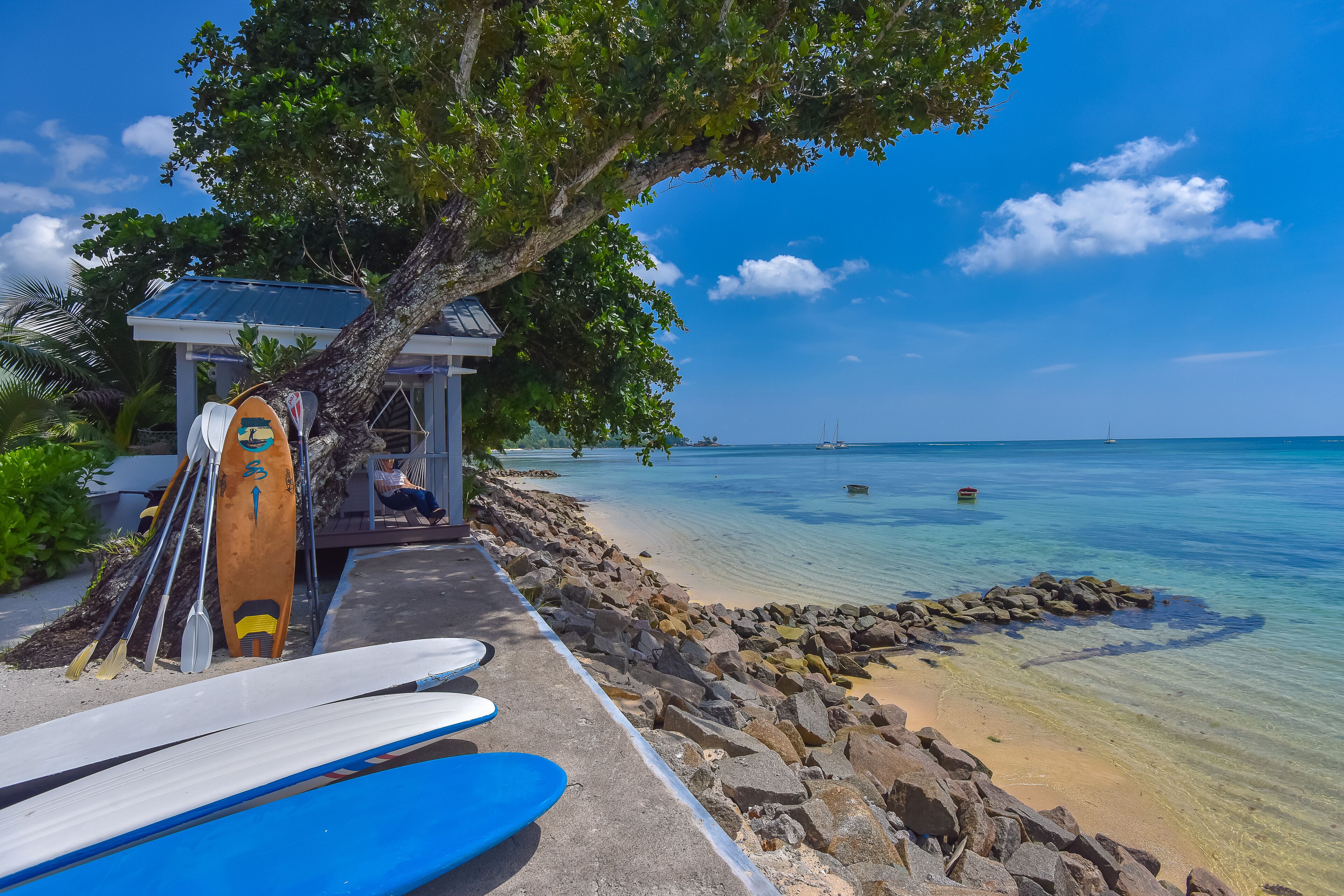 A beachside area with surfboards, a small structure, and a clear view of the ocean.