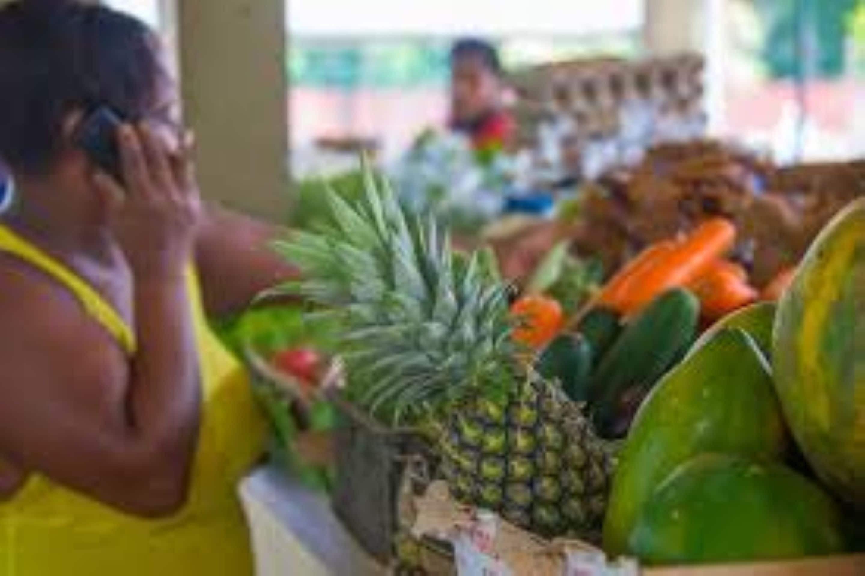 A market stall with various fruits and vegetables, including pineapples and watermelons.