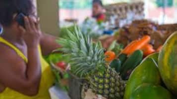 Un puesto de mercado con diversas frutas y verduras, incluyendo piñas y sandías.