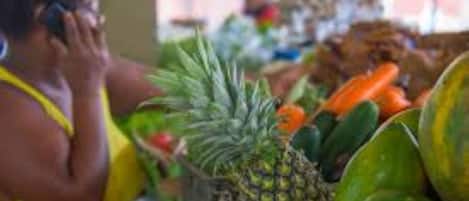 A market stall with various fruits and vegetables, including pineapples and watermelons.