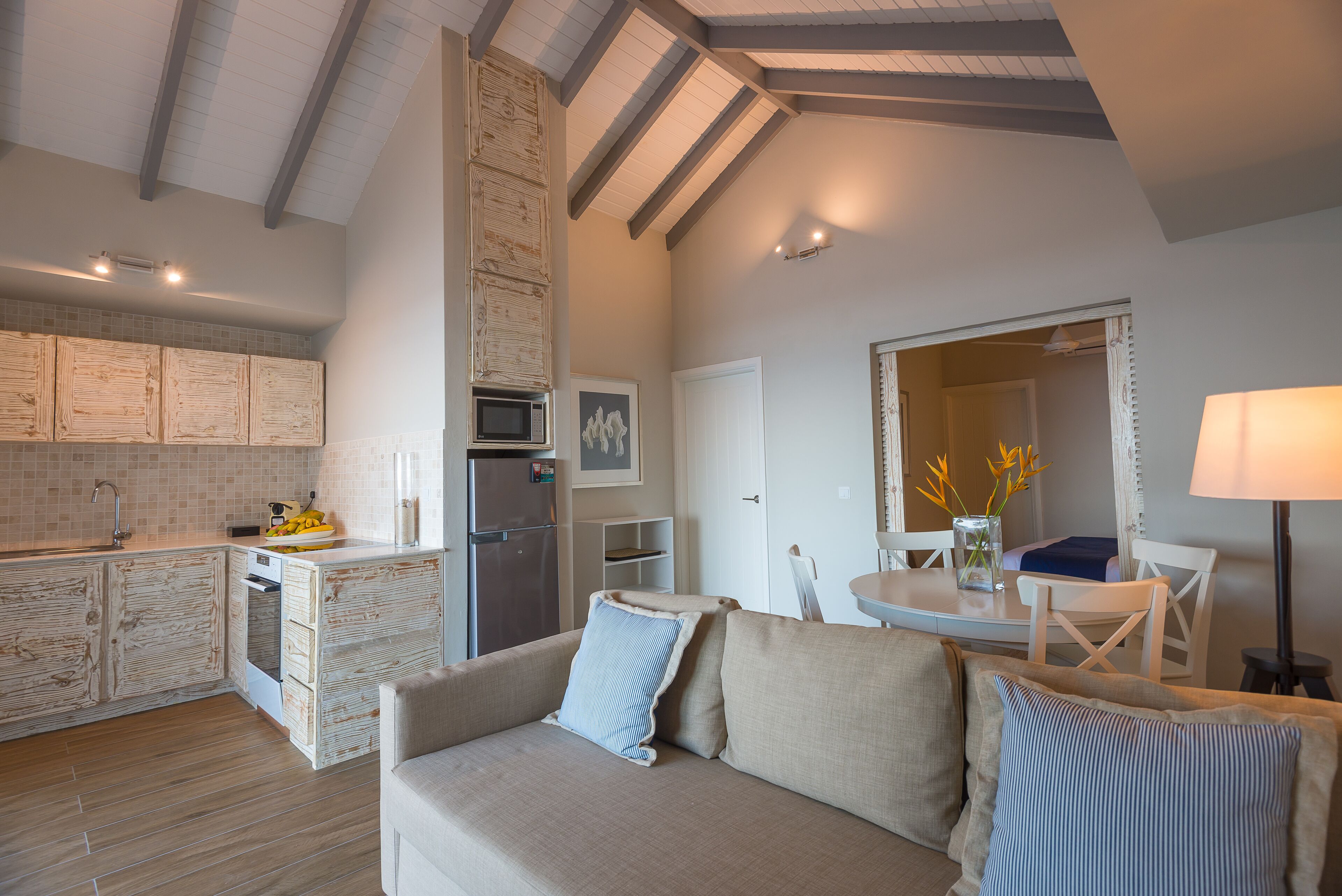 Une cuisine moderne avec des meubles en bois, un coin repas comprenant une table et des chaises, et un espace de vie chaleureux avec un canapé.