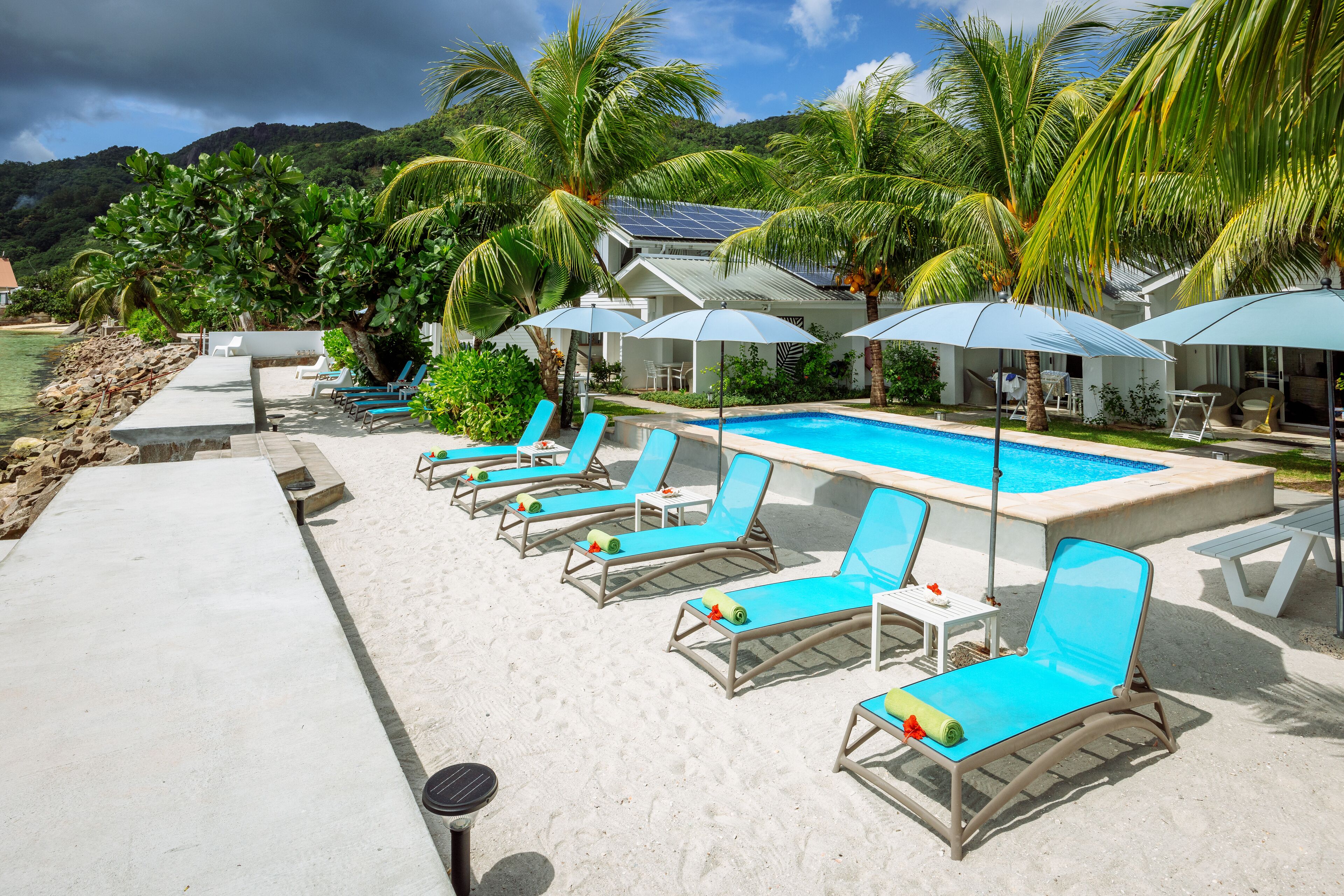 A poolside area with lounge chairs, umbrellas, and a swimming pool.