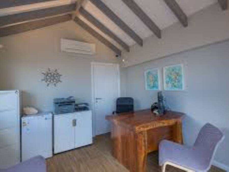 Una habitación compacta con escritorio de madera, una silla, refrigerador pequeño y lavadora.