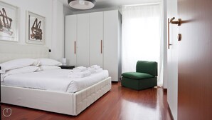 A hotel room with a bed, a green chair, and a wardrobe. - Italianway   - Zanella (Milan)