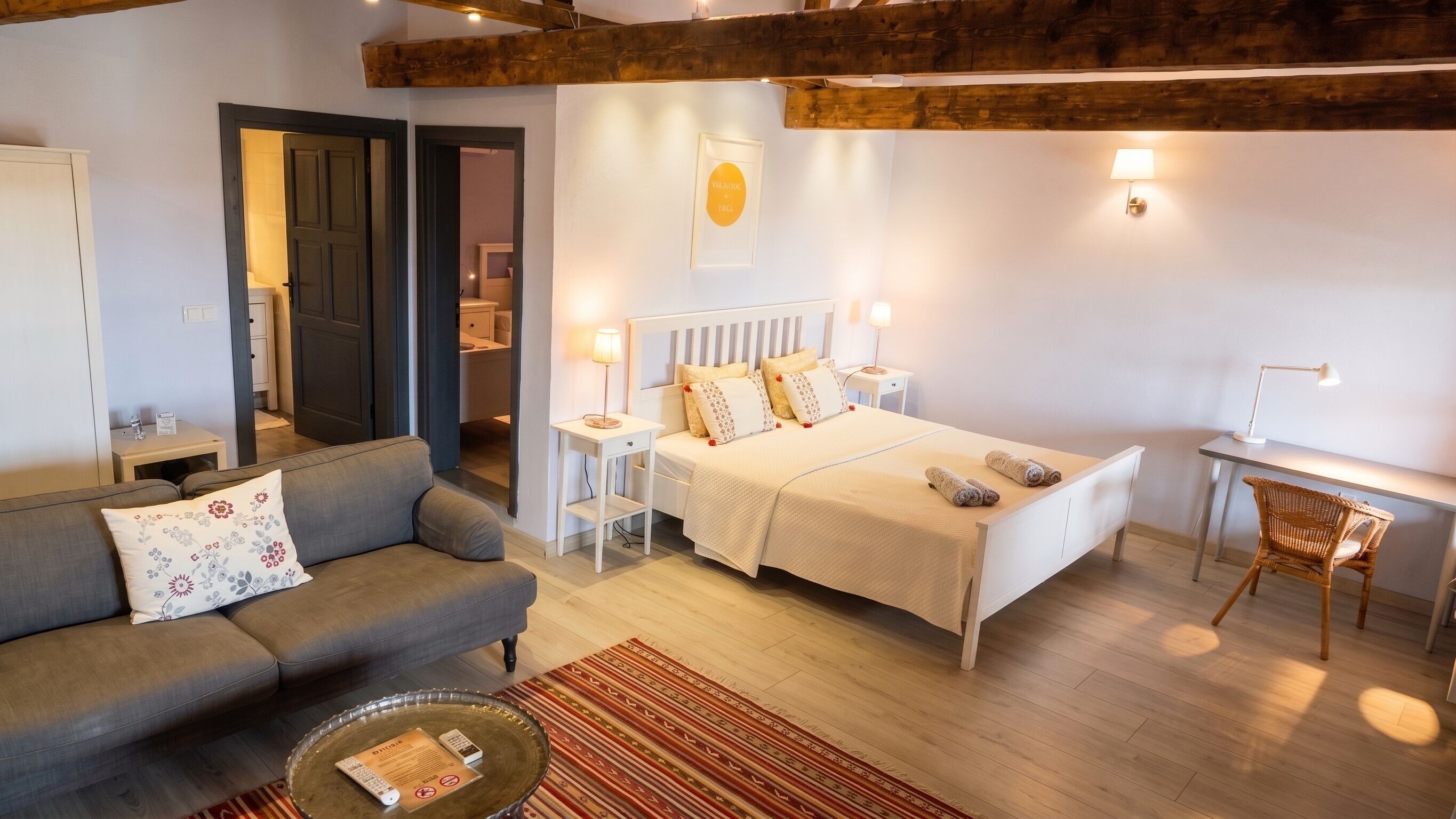A well-lit room with a bed, a sofa, a desk, and a chair.
