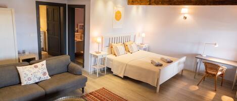 A well-lit room with a bed, a sofa, a desk, and a chair.