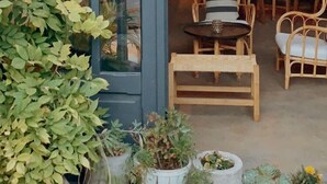 A cozy outdoor seating area with a stone fireplace, wicker furniture, and potted plants. - Attalos Suites Hotel (Bergama)
