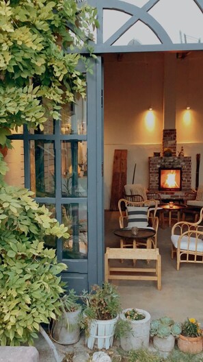 A cozy outdoor seating area with a stone fireplace, wicker furniture, and potted plants. - Attalos Suites Hotel (Bergama)