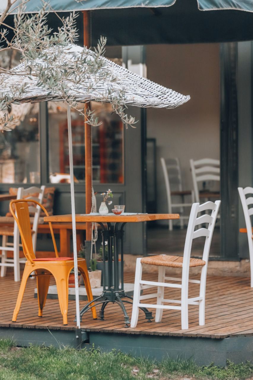 An outdoor seating area with a table and chairs, a hanging umbrella, and a view of the interior.