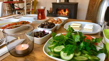 A dining table with various dishes, a candle, and a wood-burning stove in the background.