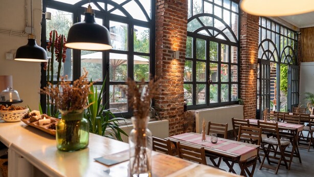 A restaurant with brick walls, large windows, and wooden tables. - Attalos Suites Hotel (Bergama)