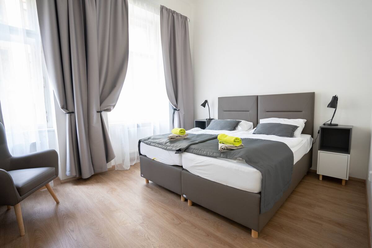 A modern bedroom with a double bed, bedside tables, a chair, and a nightstand.