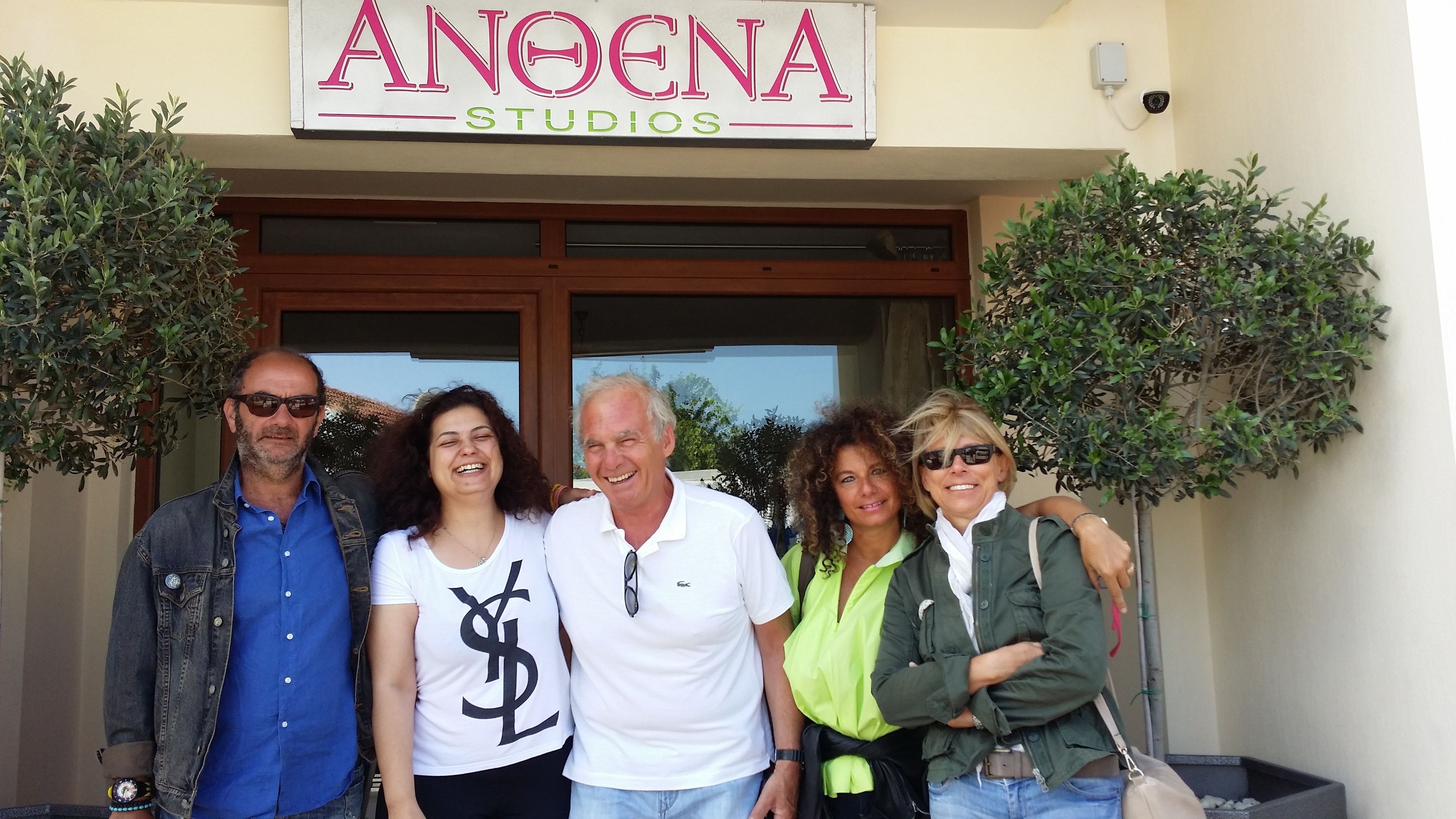 A group of people standing in front of a building with a sign that reads "ANOENA STUDIOS".