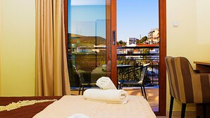 Une chambre d’hôtel avec un lit, une chaise, une table et une vue sur la ville, grâce à une grande fenêtre.