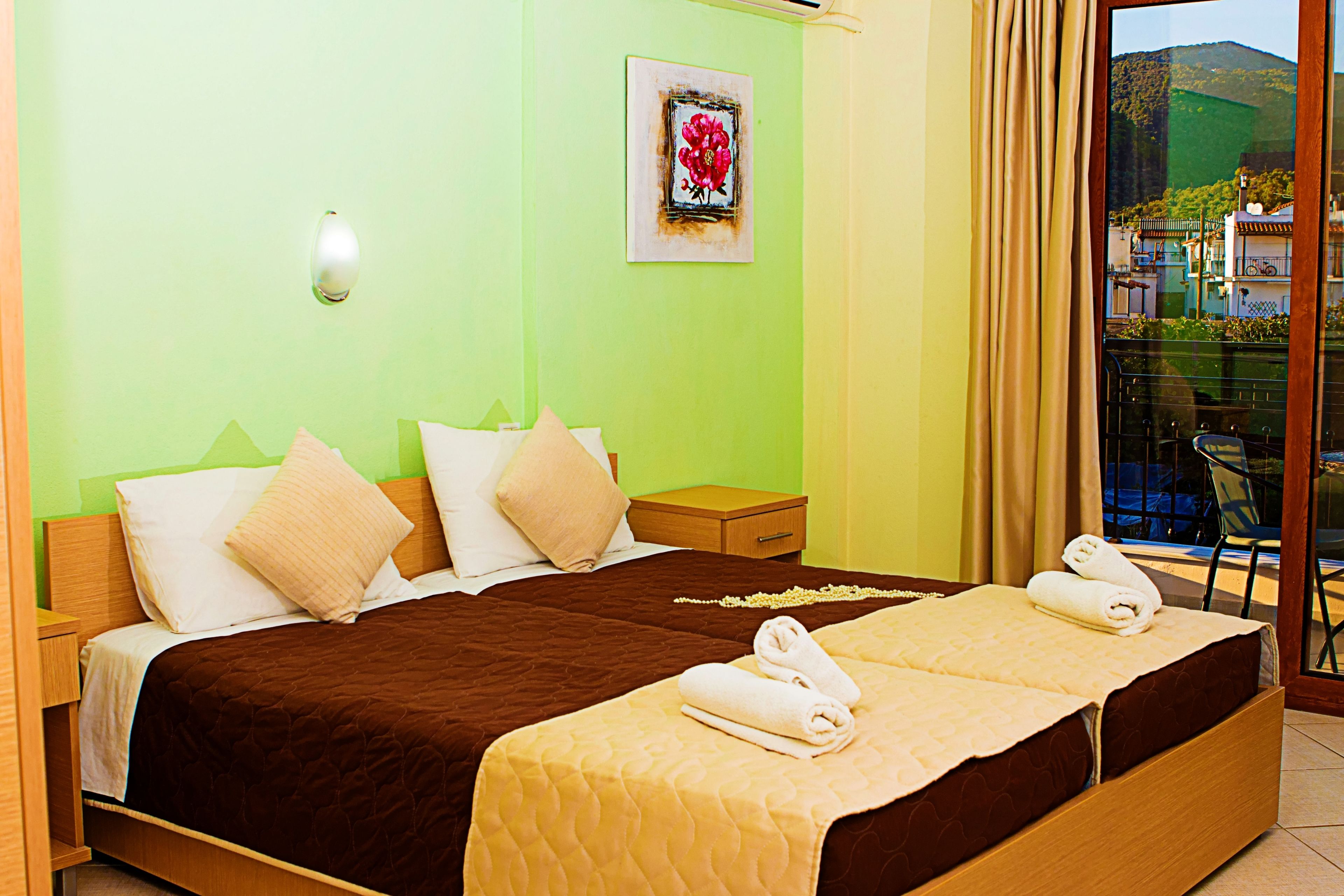 A hotel room with a bed, bedside tables, a nightstand, a window with curtains, and a view of the outside.