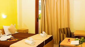 Une chambre d’hôtel avec un lit, une table de chevet, une chaise, une table et une fenêtre avec des rideaux.
