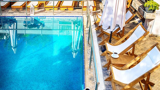 Un espace piscine équipé de chaises longues et de parasols.