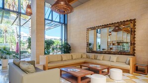 A spacious lobby with a large sectional sofa, two wooden coffee tables, and a large mirror on the wall. - TUI FAMILY LIFE Islantilla (Isla Cristina)