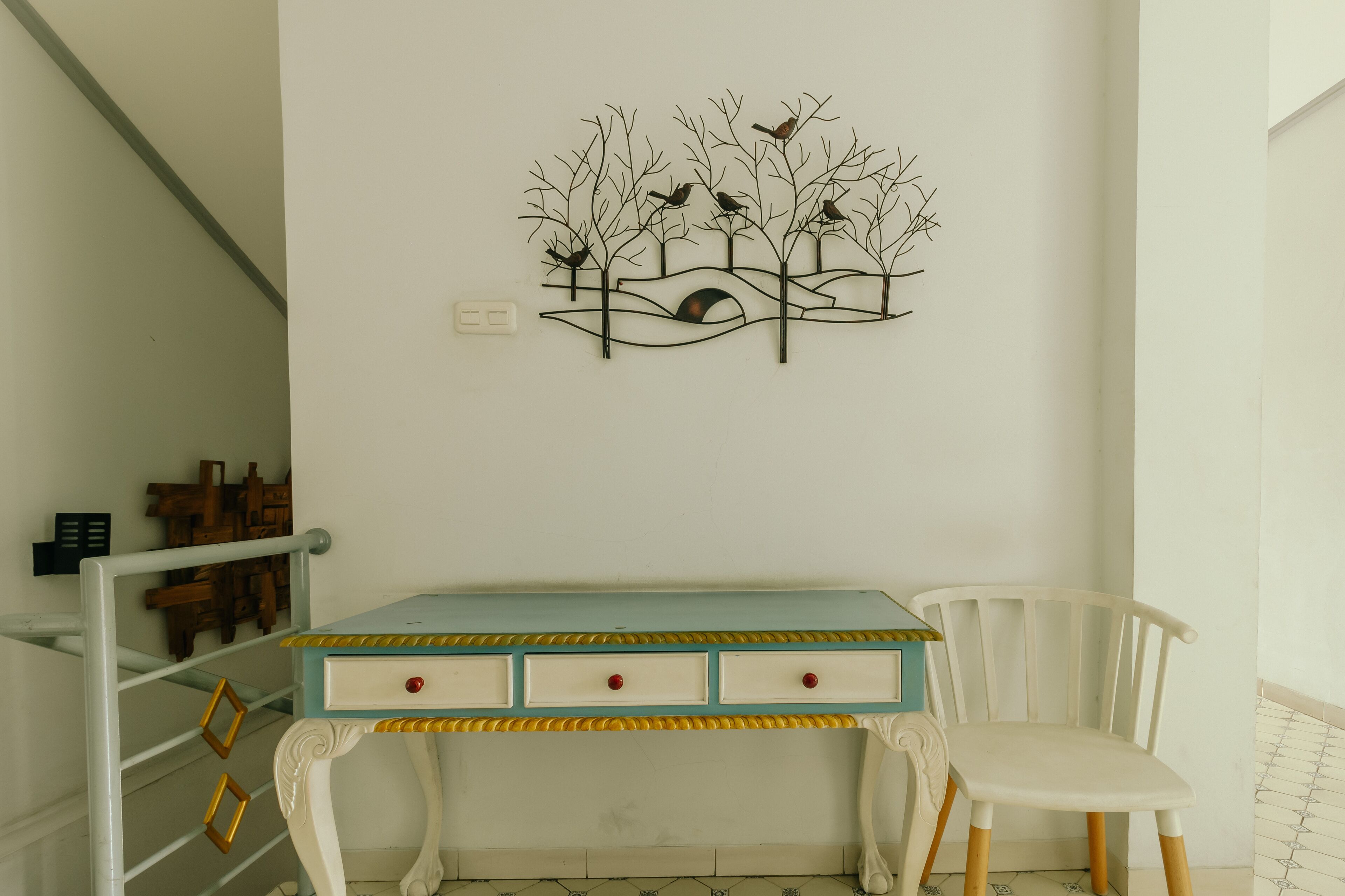 A room with a desk, chair, and a wall-mounted artwork.