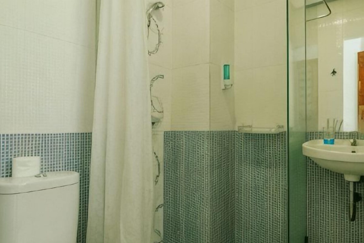 A bathroom with a shower, a toilet, and a sink.