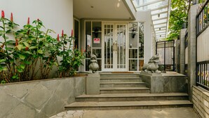 A stone staircase leading to a door with a sign, surrounded by plants and a metal gate. - Urbanest Inn House TB Simatupang (Jakarta)