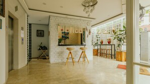 A modern kitchen with a white brick wall, wooden stools, and potted plants. - Urbanest Inn House TB Simatupang (Jakarta)