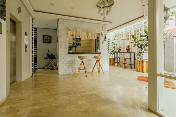 A modern kitchen with a white brick wall, wooden stools, and potted plants. - Urbanest Inn House TB Simatupang (Jakarta)