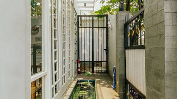 A narrow indoor corridor with a glass ceiling, a water feature, and a tiled floor.